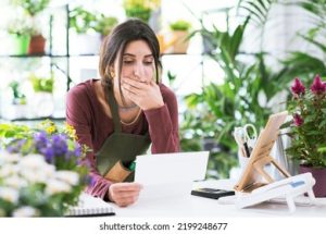 Small business owner looking worried over bills or cash register
